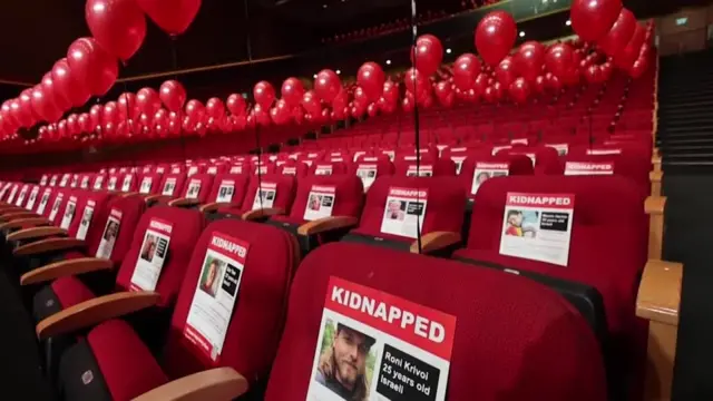 Rows of red seats each with a red balloon tied to it and a kidnapped poster showing a different hostage