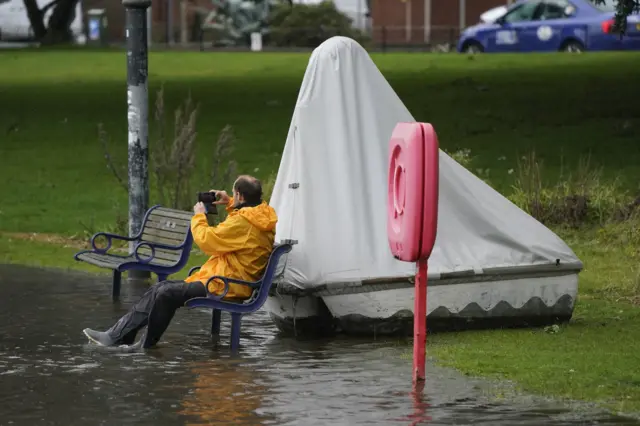 A person sitting on a submerged bench at Canoe Lake, Southsea, Portsmouth as Storm Ciaran brings high winds and heavy rain along the south coast of England. The Environment Agency has issued 54 warnings where flooding is expected, and an amber weather warning is in place with winds expected to reach 70mph to 80mph.