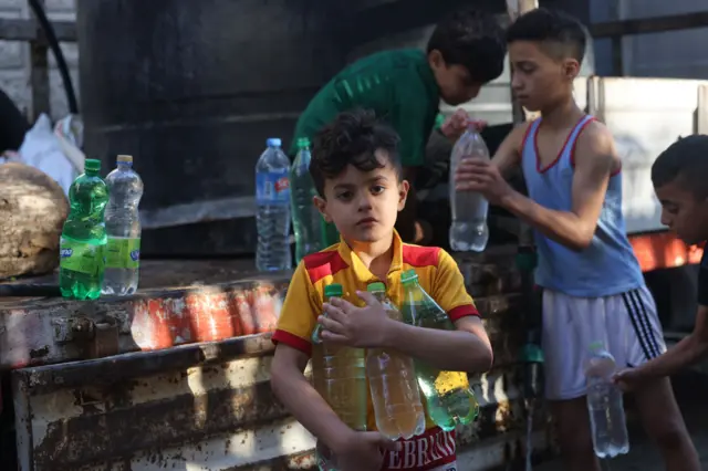 Palestinian boys fill bottles with water from a mobile cistern in Rafah in the southern Gaza Strip on October 18, 2023