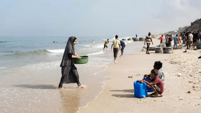 People on the beach as Palestinians resort to the use of sea water to bathe and clean their tools and clothes due to the continuing water shortage in the Gaza Strip