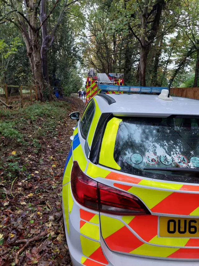 A police car and fire engine on a country road in Linton