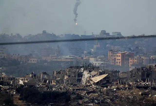 A flare fired by the Israeli military flies over the Gaza skyline - which features numerous ruined buildings