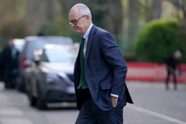 Sir Patrick Vallance walking in a suit into the Covid inquiry with his hands in his pockets