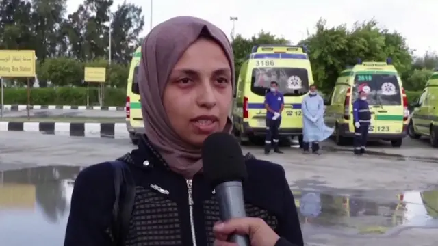 The mother of a premature baby is being interviewed in front of ambulances