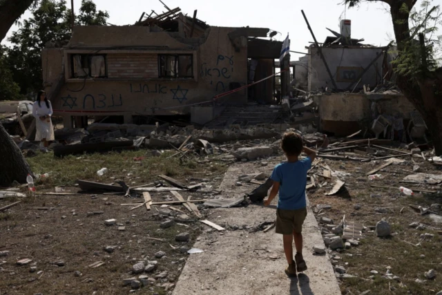 A child looks at a house hit by a rocket fired from the Gaza Strip, in central Israel, amid the ongoing conflict between Israel and the Palestinian Islamist group Hamas, in central Israel, 3 November, 2023