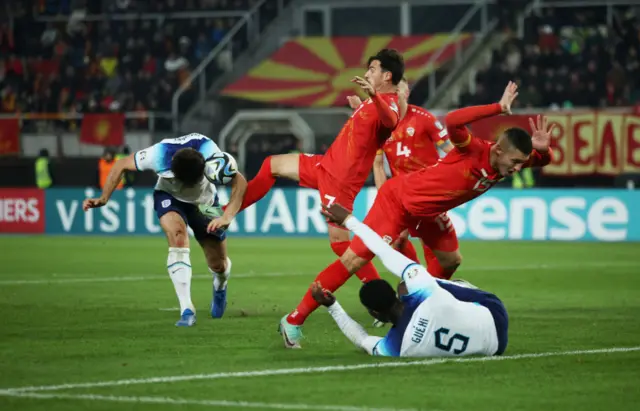 Maguire ducks to head the ball as a North Macedonia player kicks high.