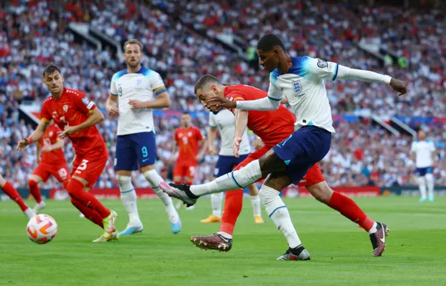 Rashford shoots the ball towards goal while a North Macedonia defender shuttles by.