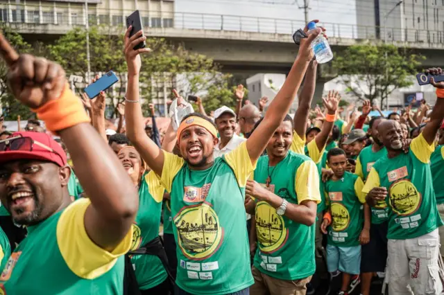 Runners wave and cheer during the 23rd edition of the Great Ethiopian Run at the Meskel Square in Addis Ababa on November 19, 2023