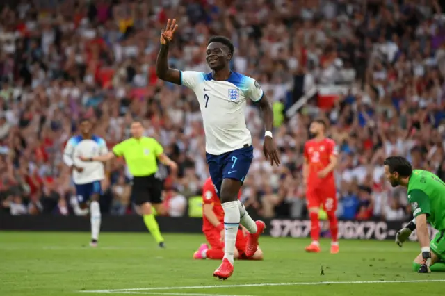 Saka holds up three fingers to celebrate him scoring a hat-trick.