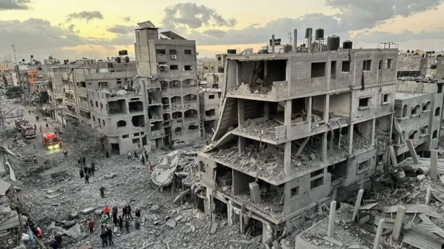 Palestinians walk among ruined houses in the Jabalia refugee camp