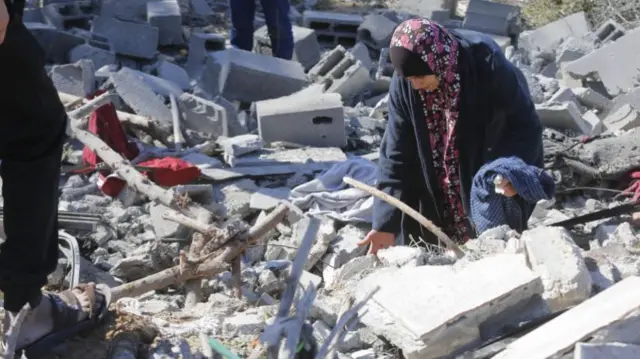 A woman lifts a block of rubble