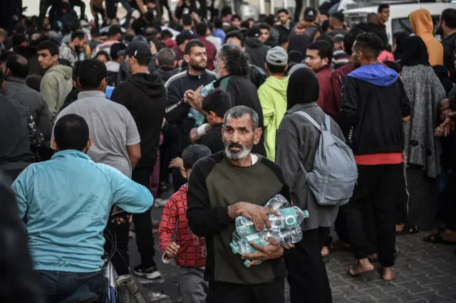 A man carries bottled water in a crowd in Khan Younis