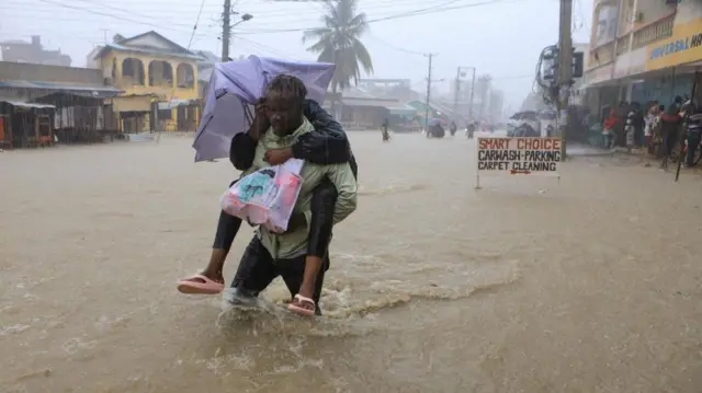 A man wades through flood waters along a street following heavy rains in Kisauni district of Mombasa, Kenya November 17, 2023.