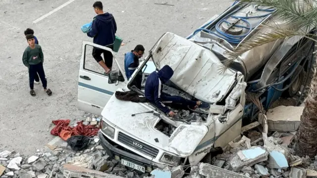 Palestinians inspect a damaged vehicle