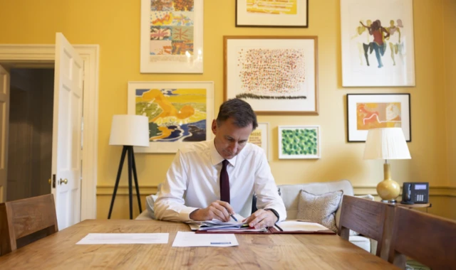 Jeremy Hunt sits at a table, working on papers