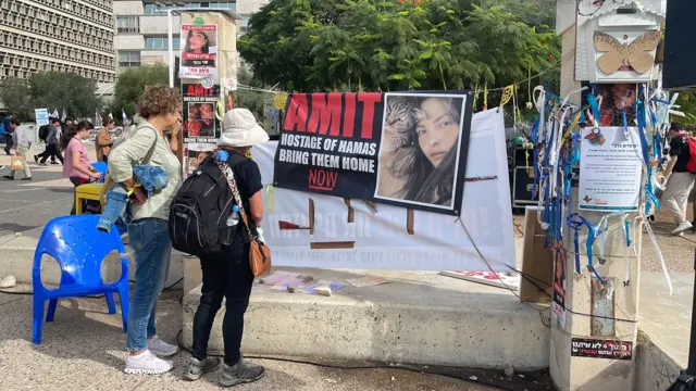 People look at the poster of an Israeli hostage in a square in Tel Aviv