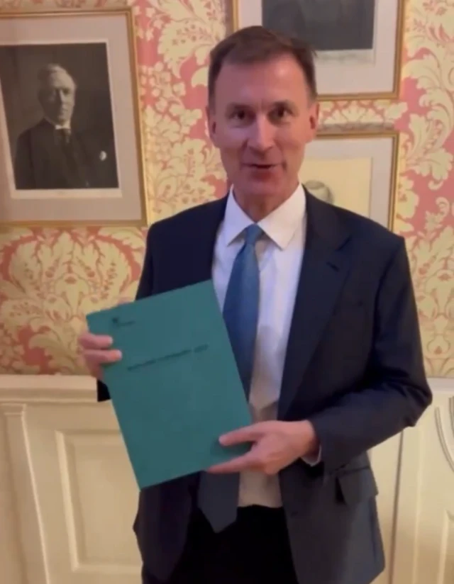 Jeremy Hunt holding the green Autumn Statement book