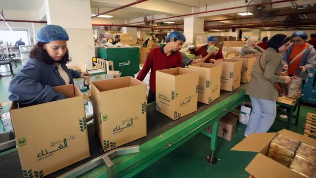 Volunteers pack boxes with food items prepared by the non-governmental organization Egyptian Food Bank for Palestinians