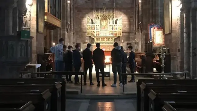 Friends of the boys bowed their heads in silence at the abbey