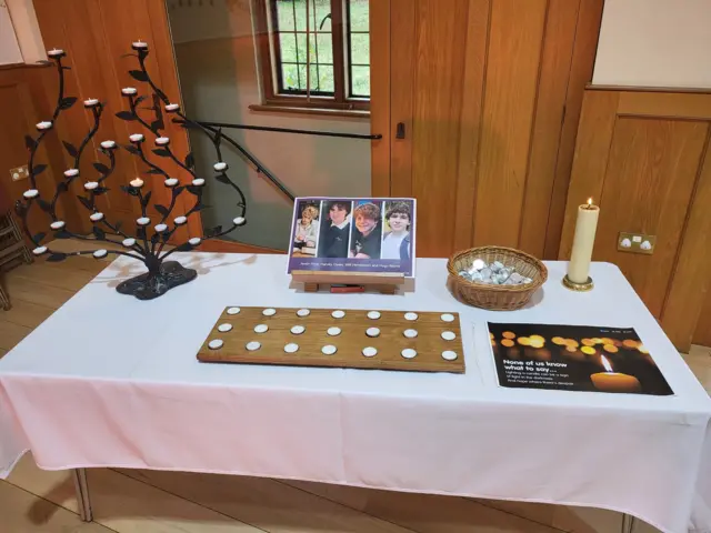 Table with a picture of the boys and candles in a church hall