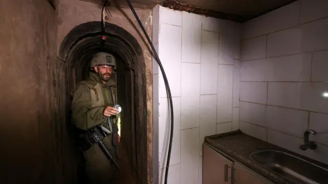 Israeli soldier with a torch in a room containing a kitchen, which Reuters says is in a tunnel underneath al-Shifa hospital