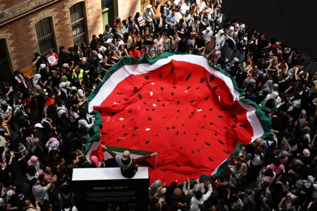 Protesters hold a large flag in the shape of a watermelon at Flinders Street Station in Melbourne