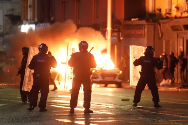 Police officers next to a burning car in Dublin