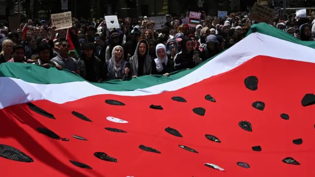 Protesters hold a large flag in the shape of a watermelon at Flinders Street Station in Melbourne