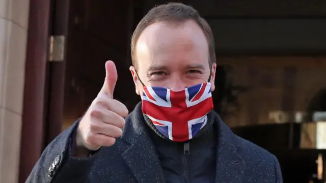 Matt Hancock wears a face mask with a union jack on it and gives a thumbs up