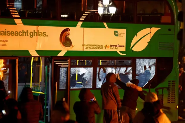 People smashing the windows of a bus