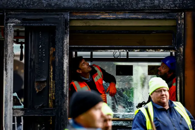 Workers assess the damage to a burnt out tram in Dublin