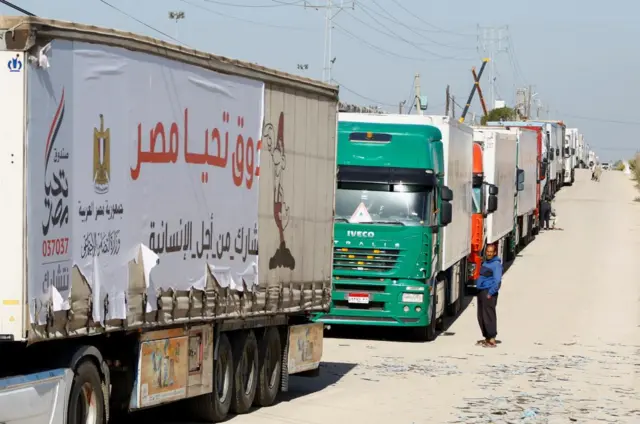 Long line of lorries, a man stands nearby