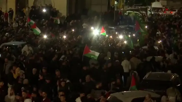 A crowd of people waving Palestinian flags