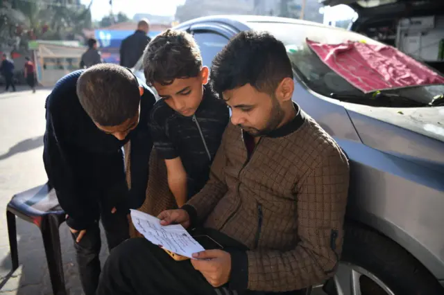 Two men and a child read a leaflet