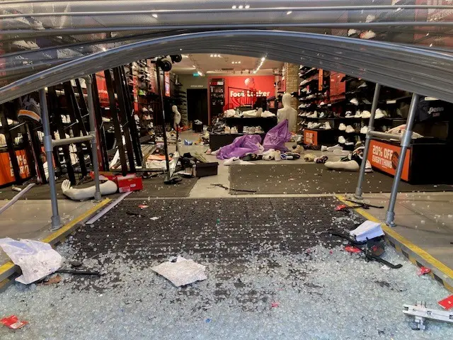 Smashed glass inside a Foot Locker store, where merchandise is strewn around