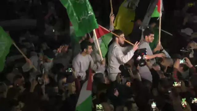 A group of men ride on peoples' shoulders in the crowds in Beitunia