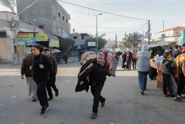 A man carrying a blanket through Gaza