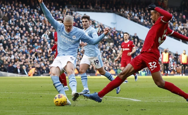 Erling Haaland shoots as Matip attempts to block his shot