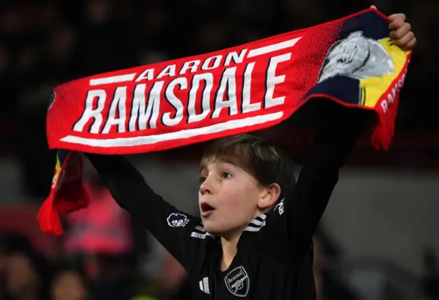 A fan holds up an Aaron Ramsdale scarf during the game.