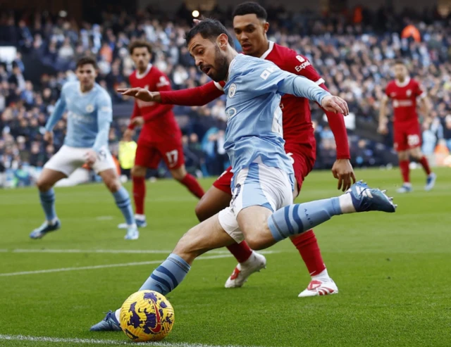 Bernard Silva crosses the ball in as Trent Alexander looks on