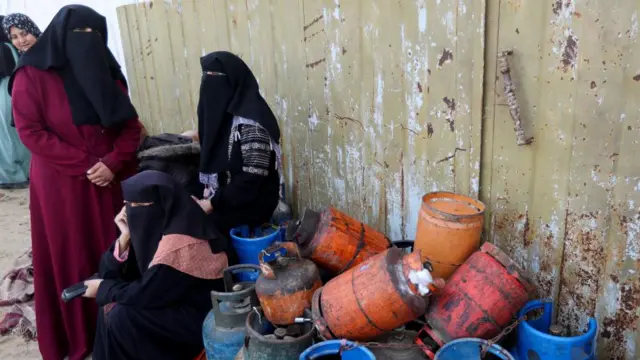 Palestinian women gather to fill liquid gas containers