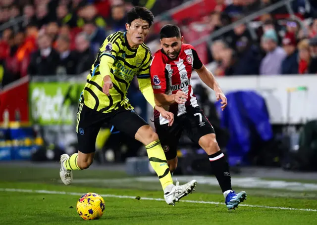 Neal Maupay tussles with Arsenal's Takehiro Tomiyasu.