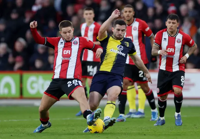 James McAtee and Lewis Cook challenge for the ball.