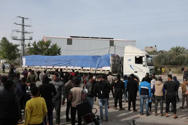 An aid truck moves on a road as Palestinians look on, during a temporary truce between Hamas and Israe