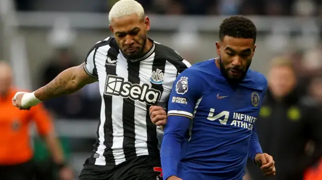 Joelinton and Reece James challenge for the ball.