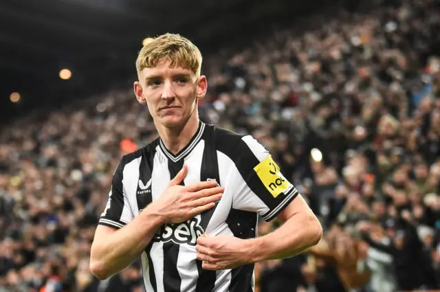 Anthony Gordon taps the Newcastle badge on his shirt.