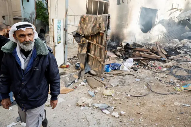 Palestinians check the damage in a street in the aftermath of an Israeli raid in Jenin