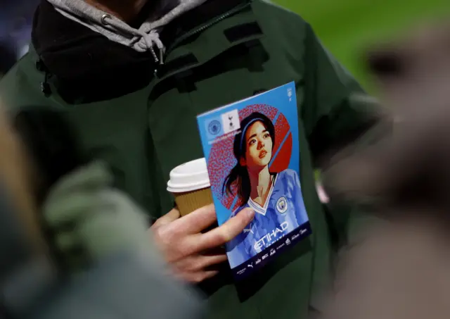 A Manchester City fan holds a program