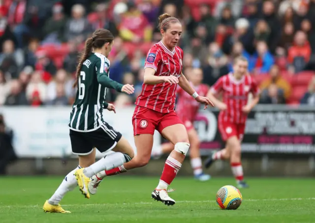 Naomi Layzell drives the ball forward under pressure from Hannah Blundell.