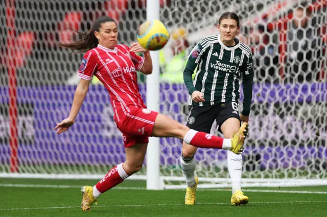 Hannah Blundell passes the ball under pressure from Ffion Morgan.